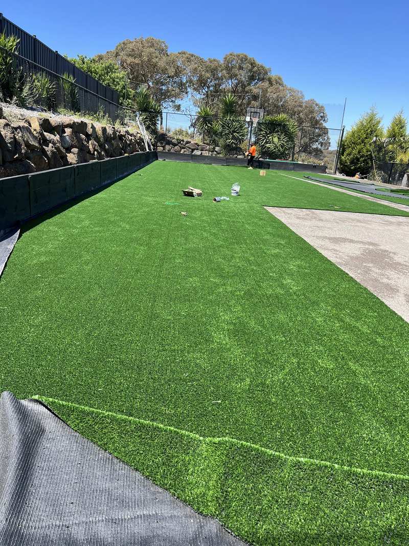 Synthetic turf being laid beneath the boulder wall