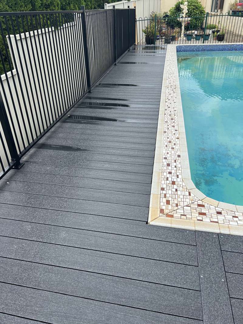 The finished composite deck running along the pool