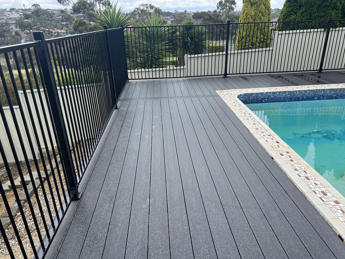 A new charcoal composite pool deck with black balustrade beside the pool